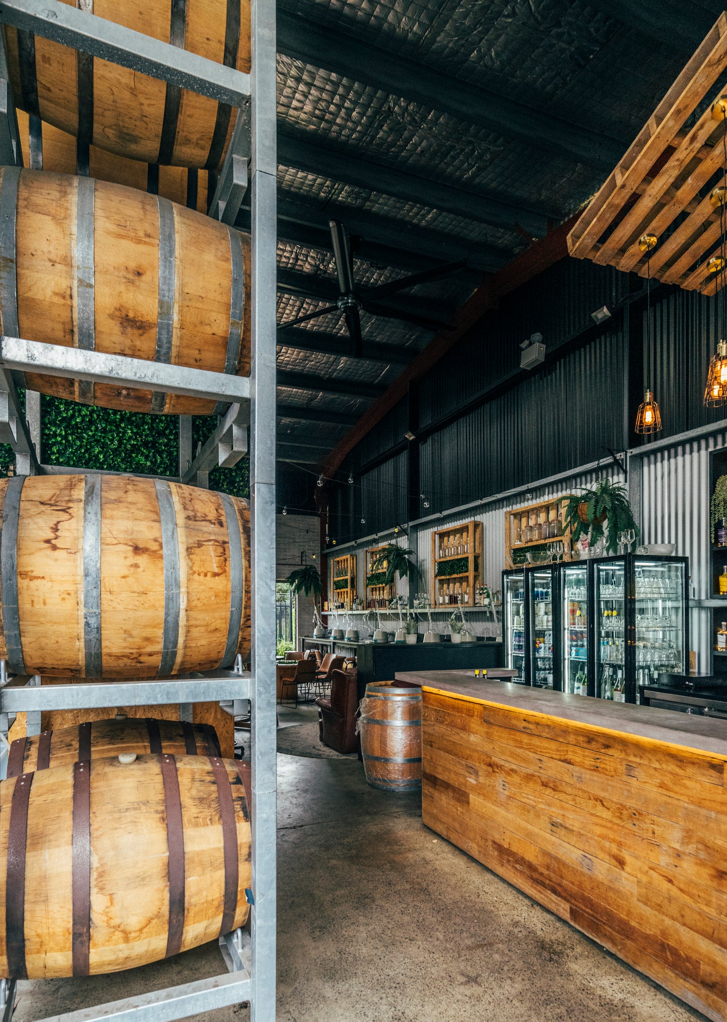 The view upon entering distillery, showcasing whiskey and geneva barrels, the bar and the door to the botanics garden