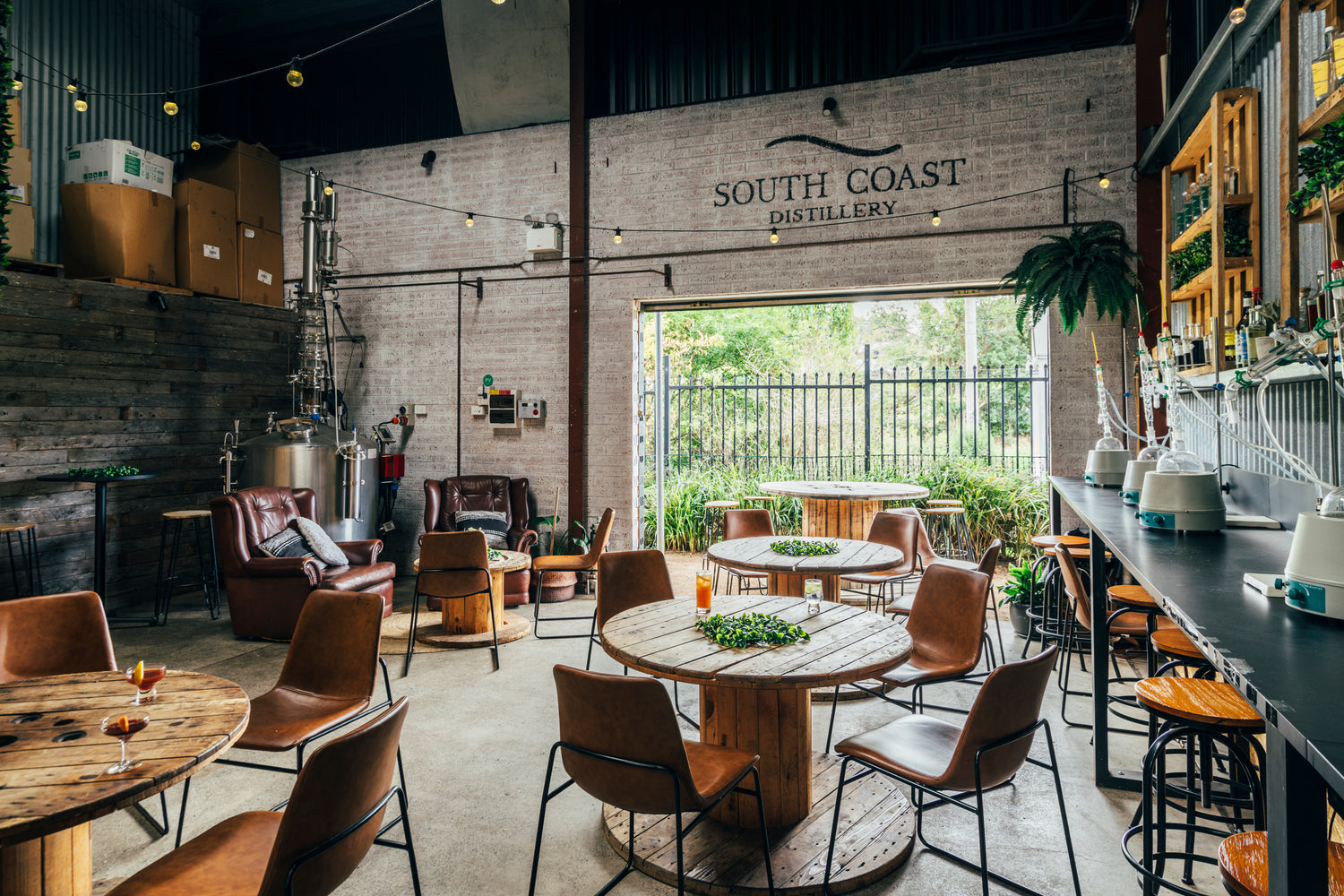 A cosy view of South Coast Distillery in Wollongong, with cocktails, a column still & a door to the botanic garden.